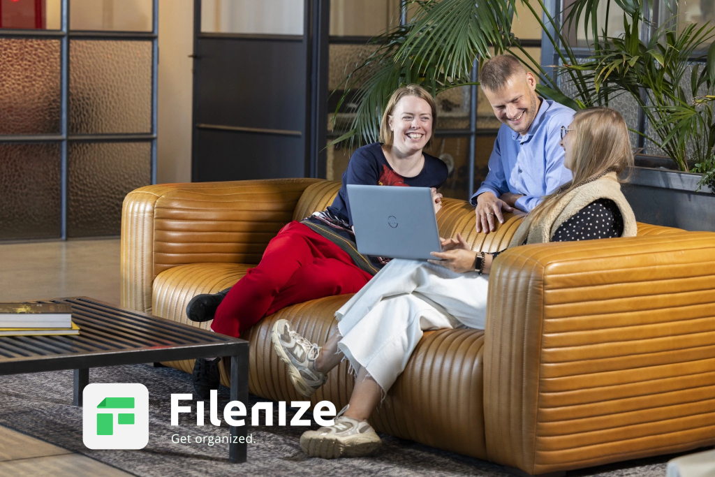 Three employees of Filenize working on a couch and showing the website and capabilities of Filenize